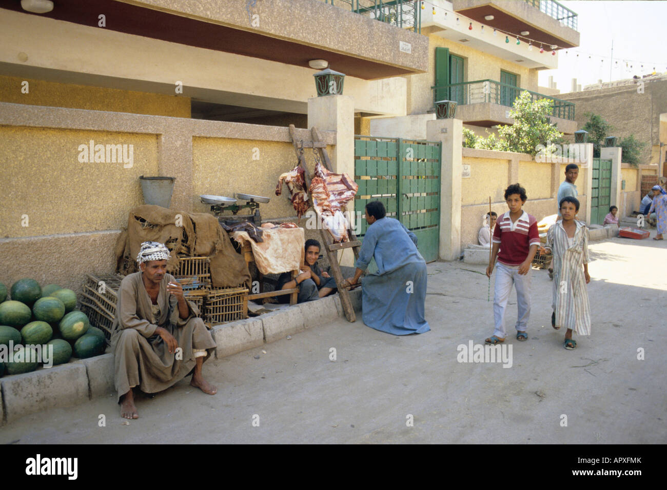 Two children walking past a watermelon seller in Luxor Stock Photo