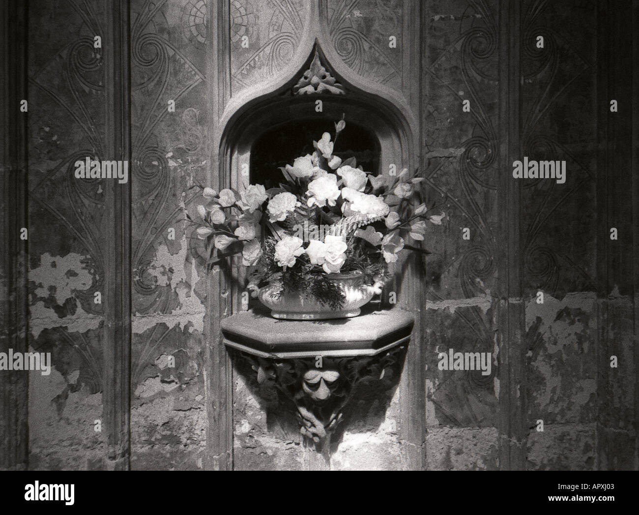 black and white image of gothic nich in wall of church with flowers Stock Photo