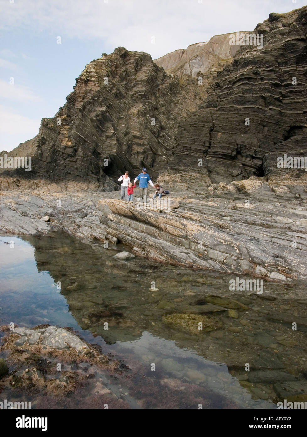 Family at the base of Constitution Hill Cliffs at Aberystwyth Ceredigion  - layers of sedimentary mudstone rocks Stock Photo