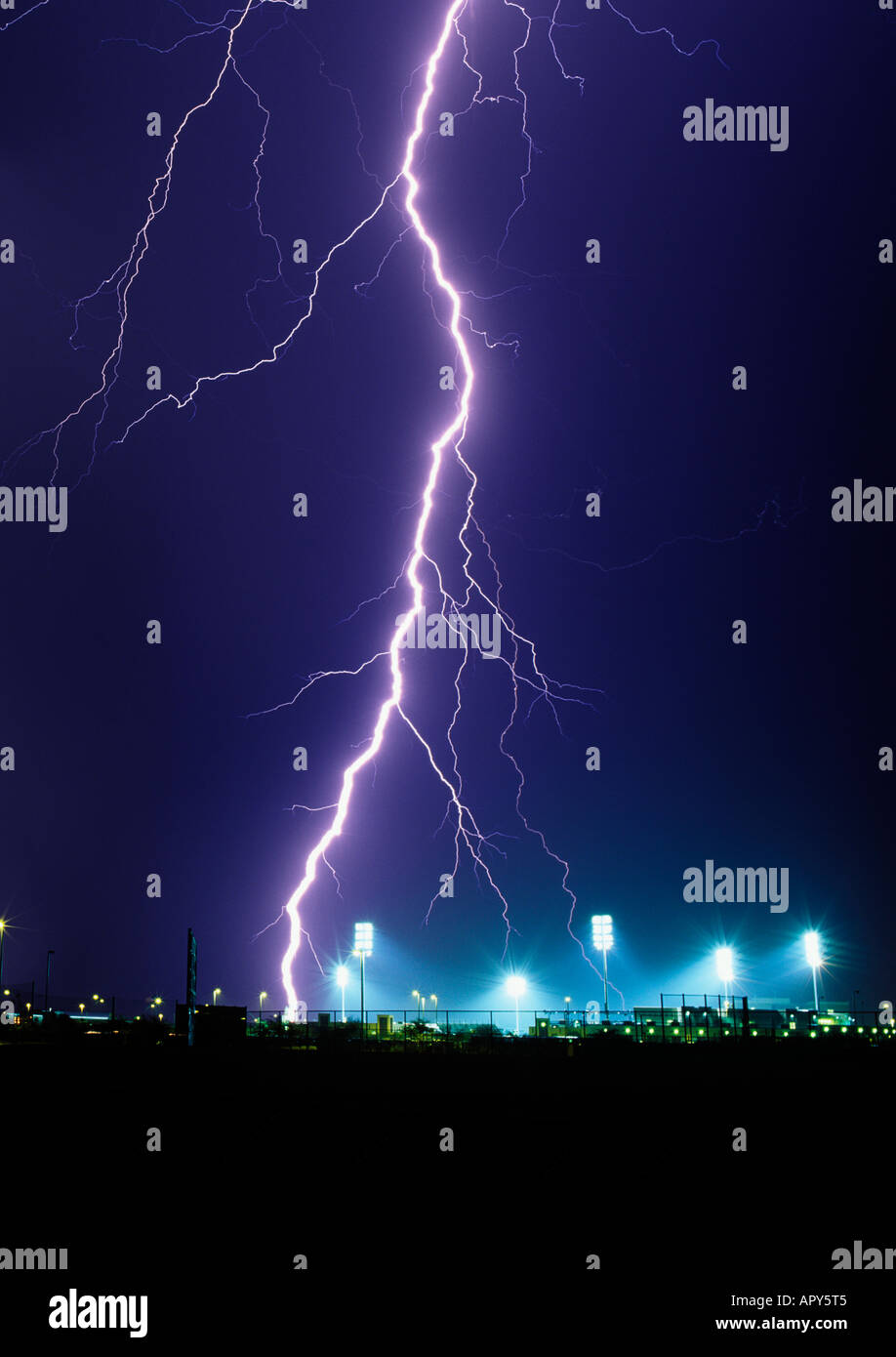 Large lightning bolt strikes down next to an illuminated baseball field during a summer monsoon storm in Tucson, Arizona, USA. Stock Photo
