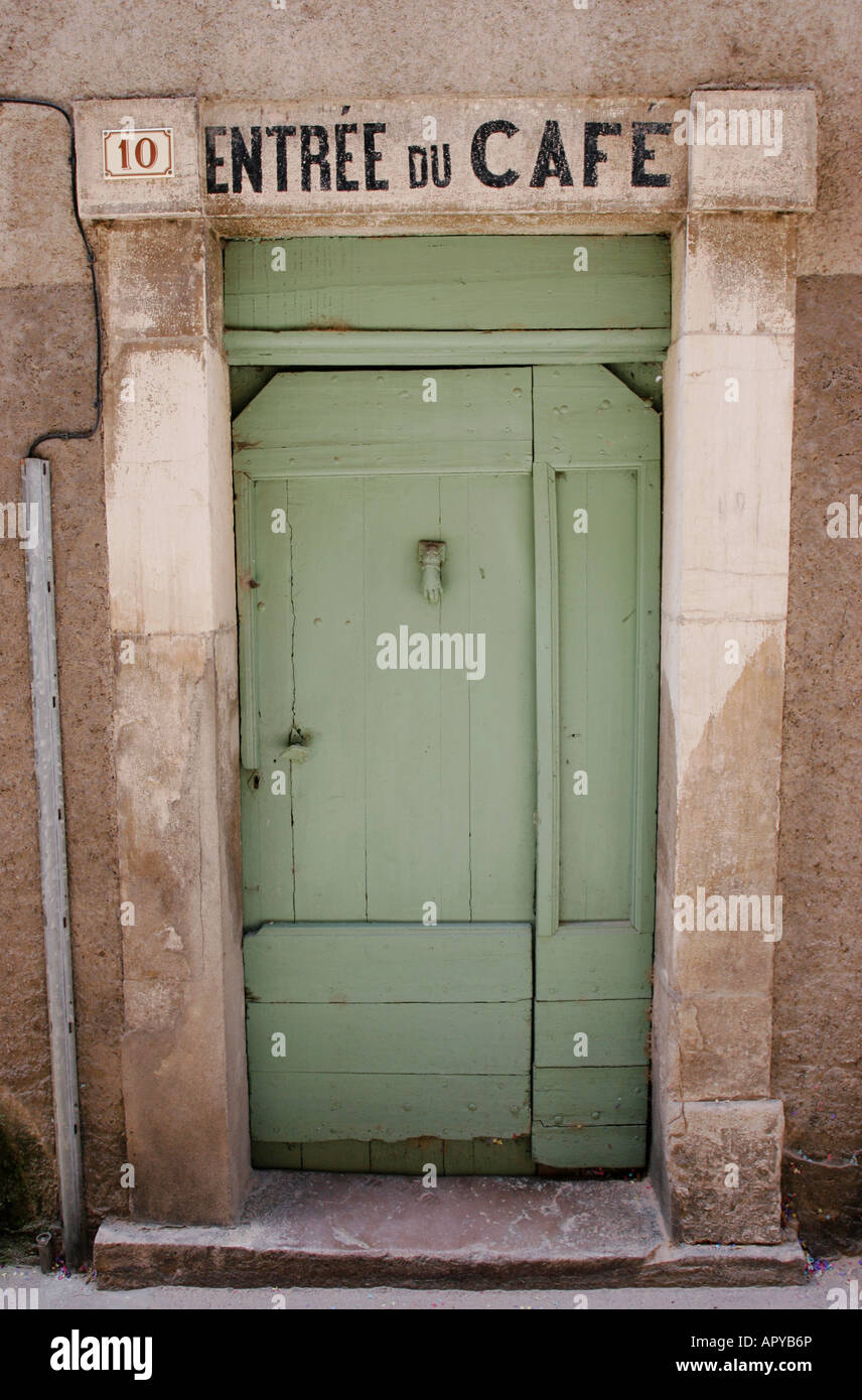 Green closed door to a French cafe with stone pillars and old painted