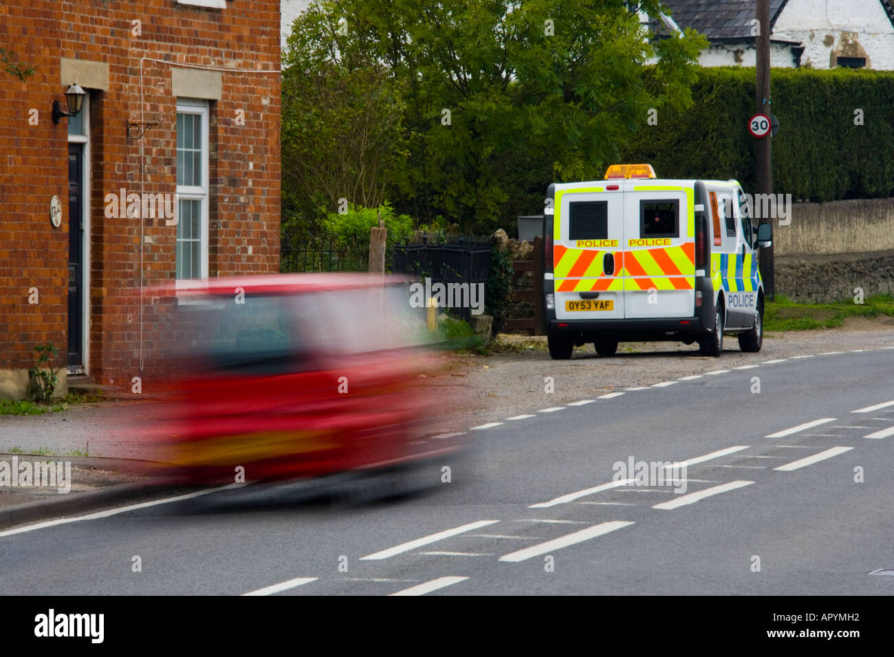 Red saloon car speeding past 30 mph police mobile speed trap traffic safety JMH1769 Stock Photo