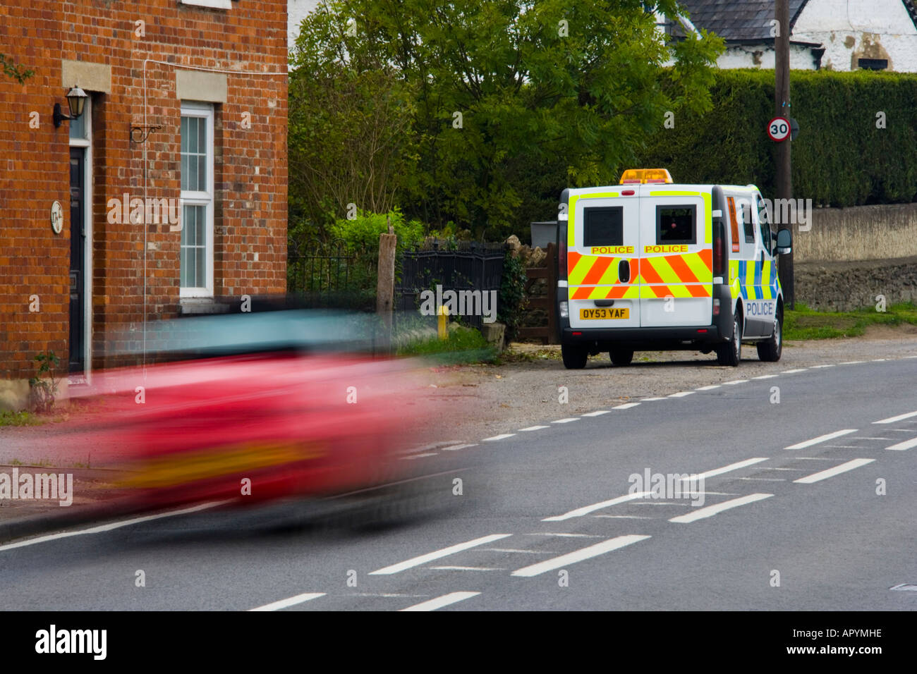 Red saloon car speeding past 30 mph police mobile speed trap traffic safety JMH1770 Stock Photo
