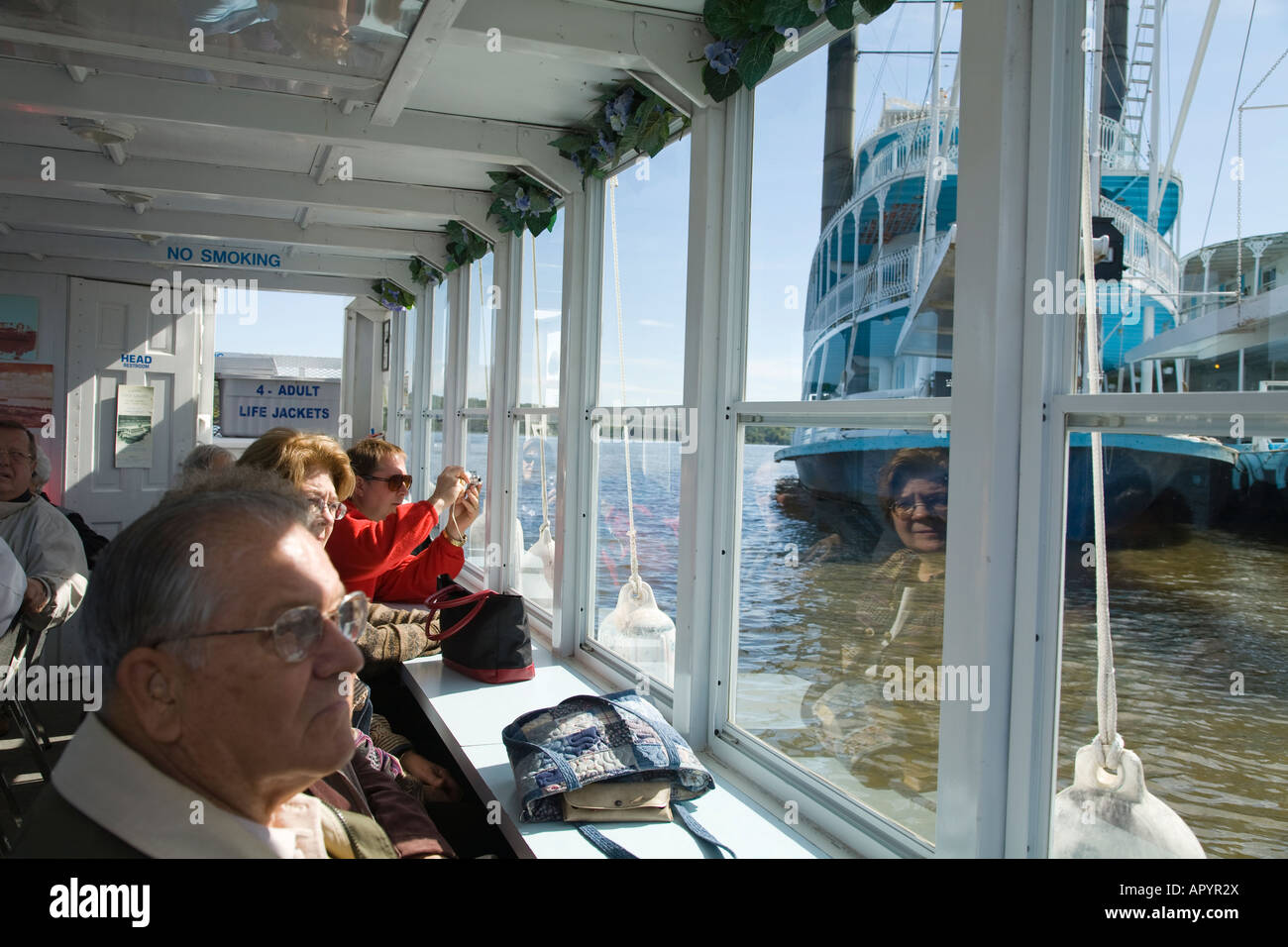 IOWA LeClaire Passengers on river tour boat looking out window passing paddlewheel boat Stock Photo