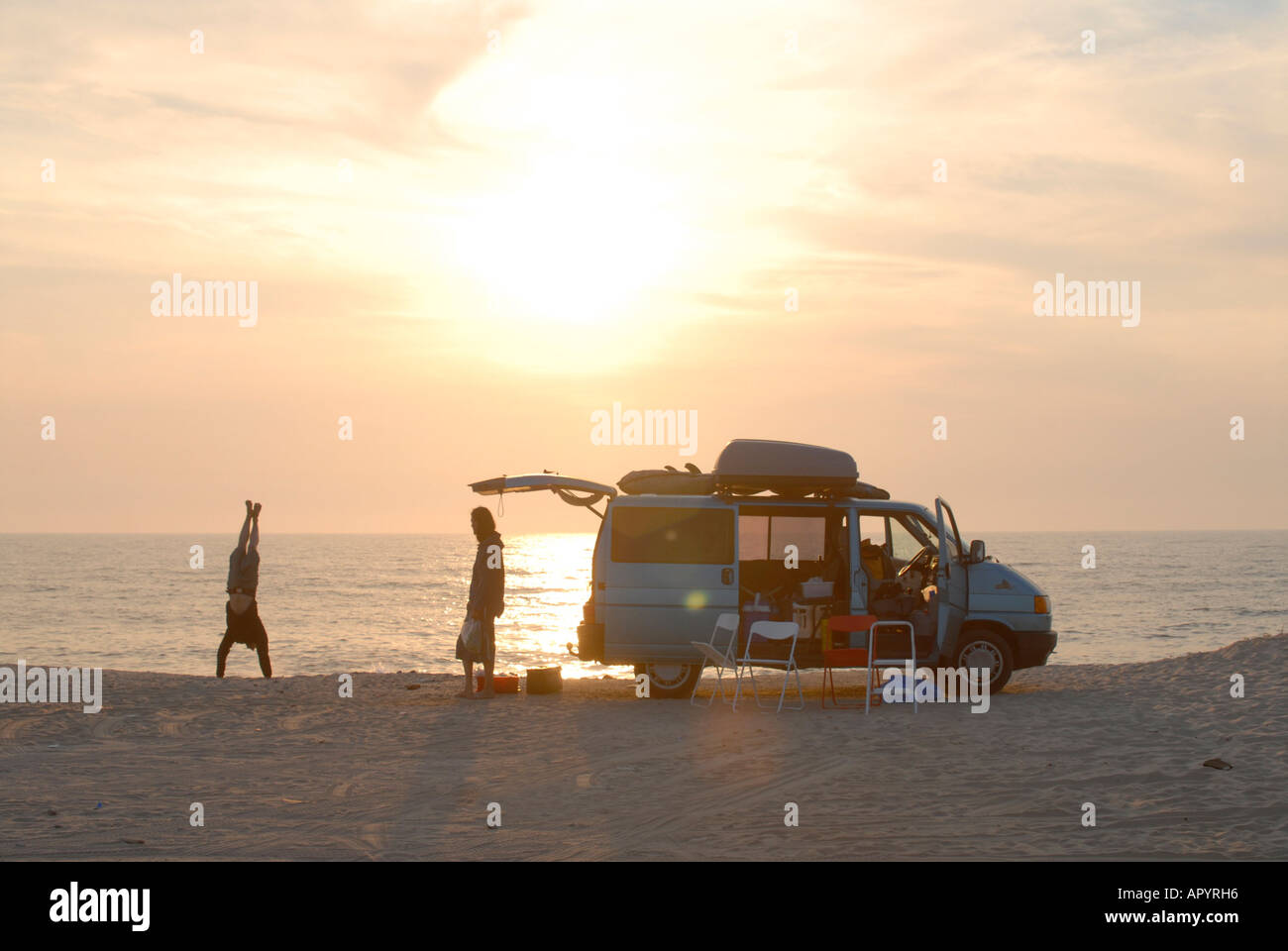 Young people enjoy the sunset at the ocean with a campmobile at the beach, atlantik, portugal Stock Photo