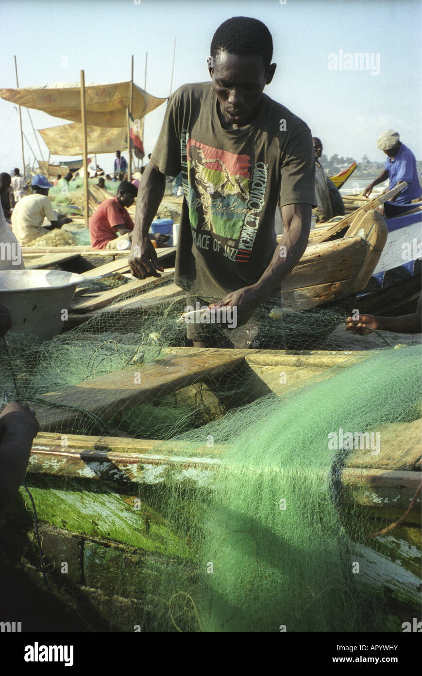 Close up of fisherman mending his nets outside Elmina Castle Cape Coast ...