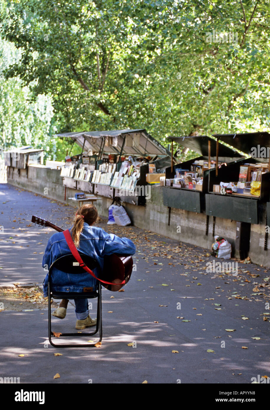 Paris bookshop stand keeper play guitar on pavement Stock Photo