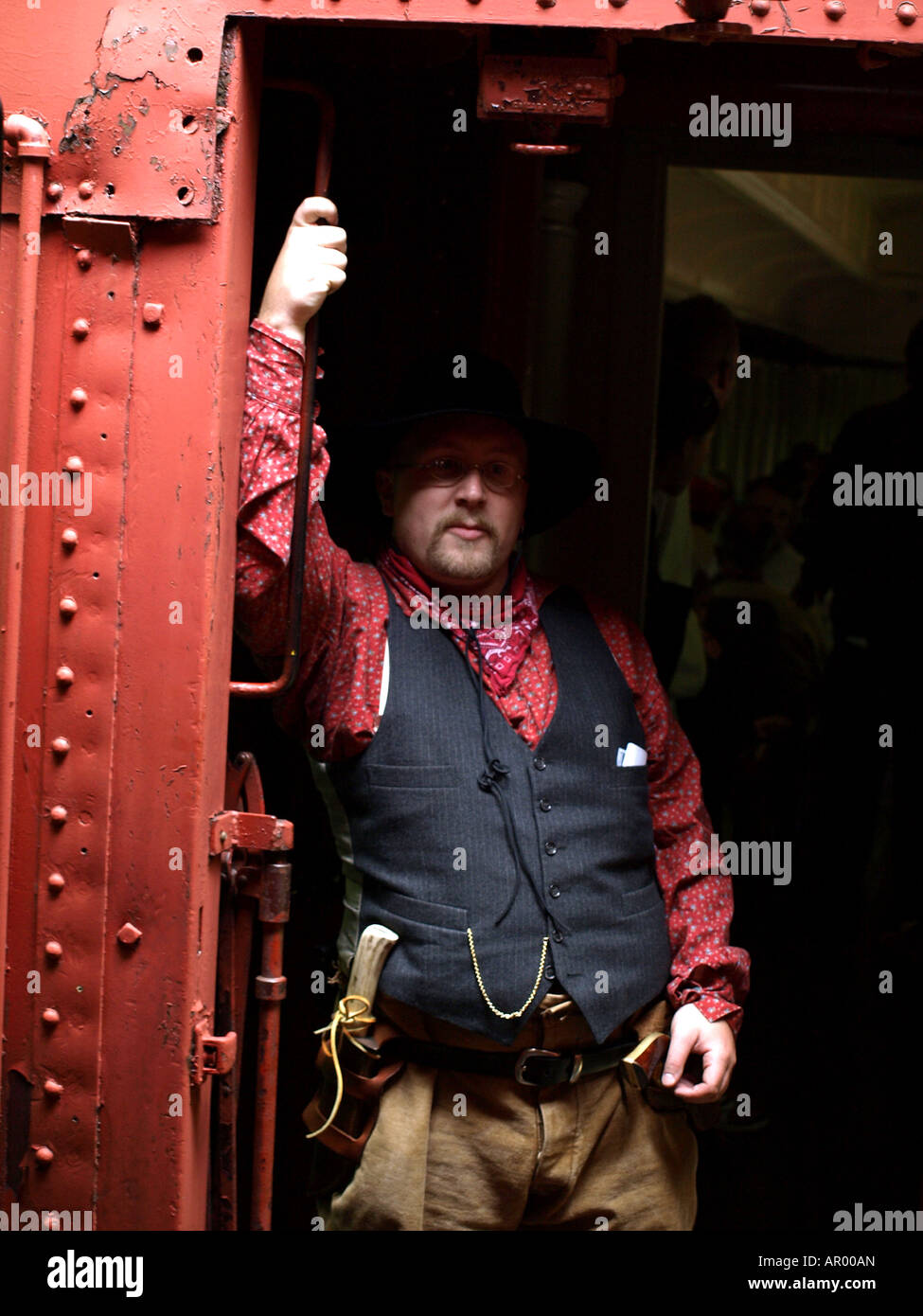 A western cowboy with a knife riding an old passenger train car Stock Photo