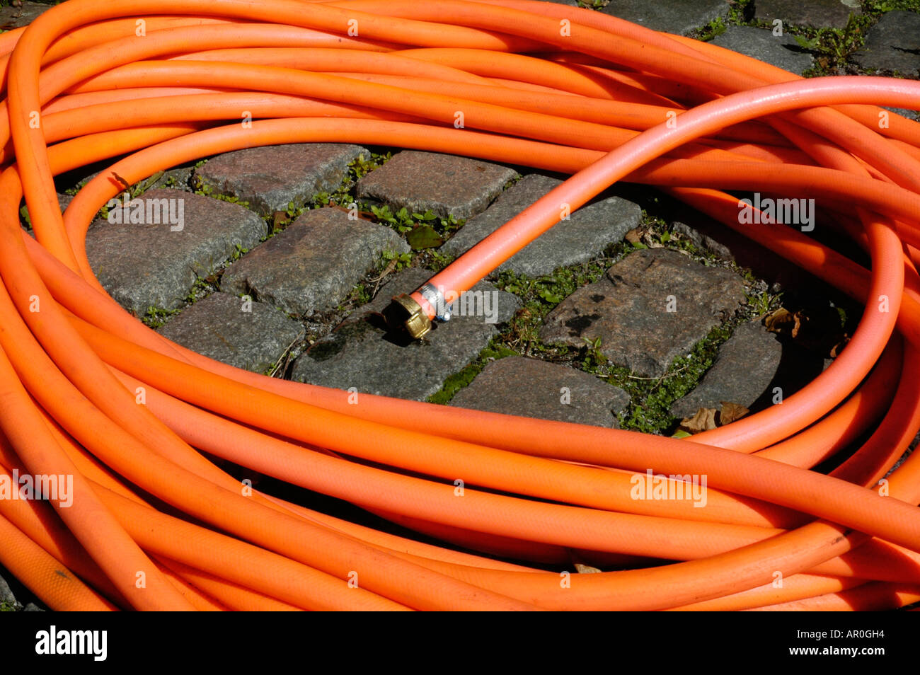 Red garden hose on cobble stones Stock Photo Alamy