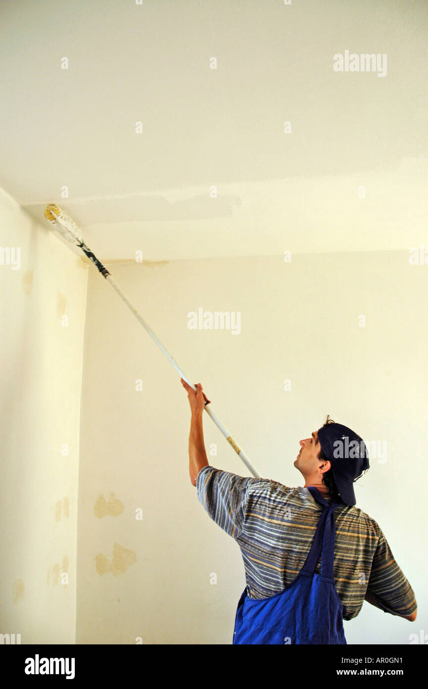 House Painter In Working Clothes Is Painting The Ceiling