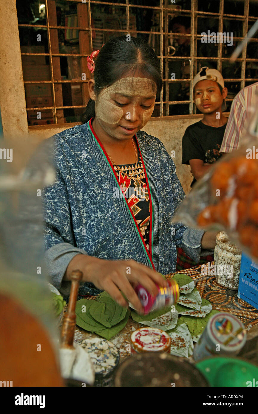 Preparing betel at a stall, Bago market, Burmese woman prepares betel leaves with slaked lime, spices and areca palm nut to sell Stock Photo