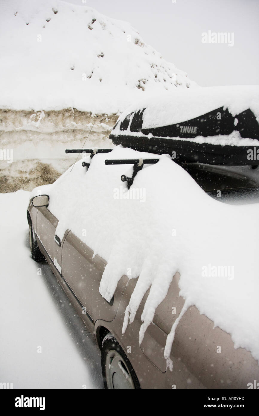 A parked car with a roof rack lies covered in snow at Snoqualmie Pass