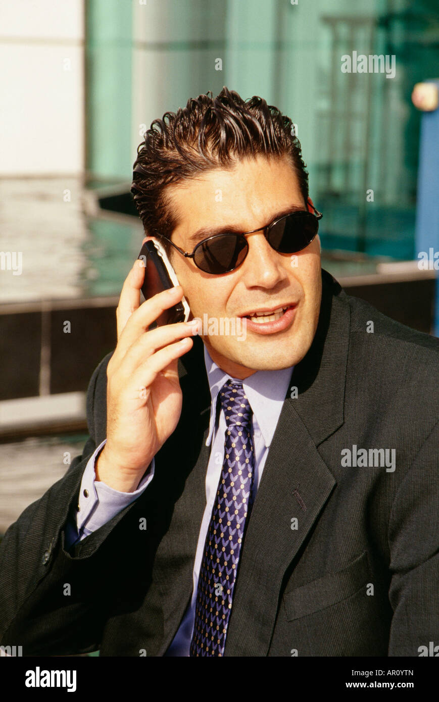 A businessman seen conversing on the cell phone on a sunny day. Stock Photo