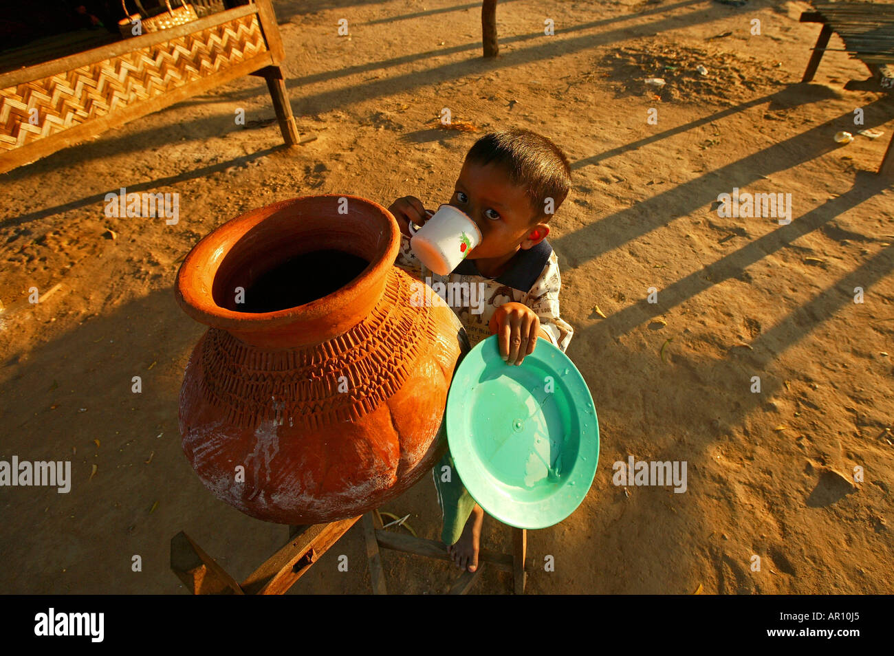 small child drinks water from water jar, Burma, Myanmar Stock Photo