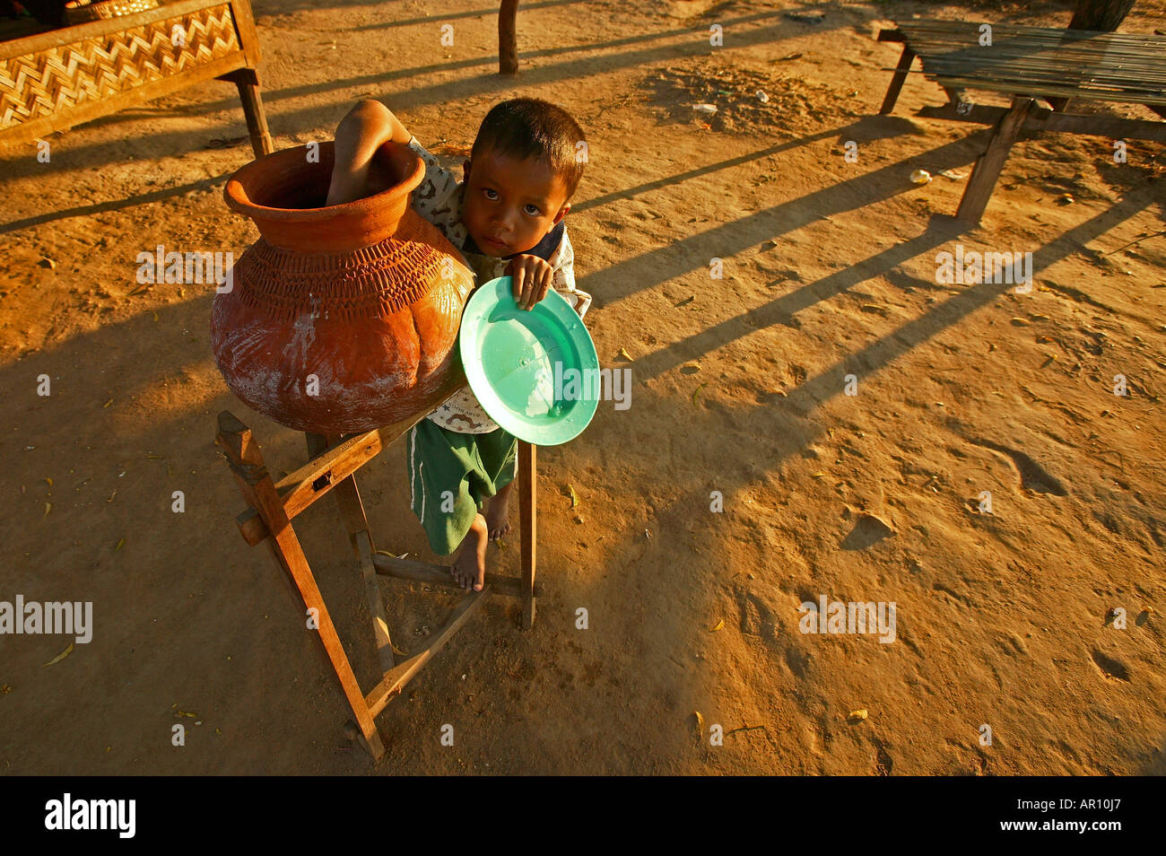 Child drinks water from terracotta pot, Junge trinkt Wasser aus Tontopf, Wasserbehaelter aus Ton, typisch Stock Photo