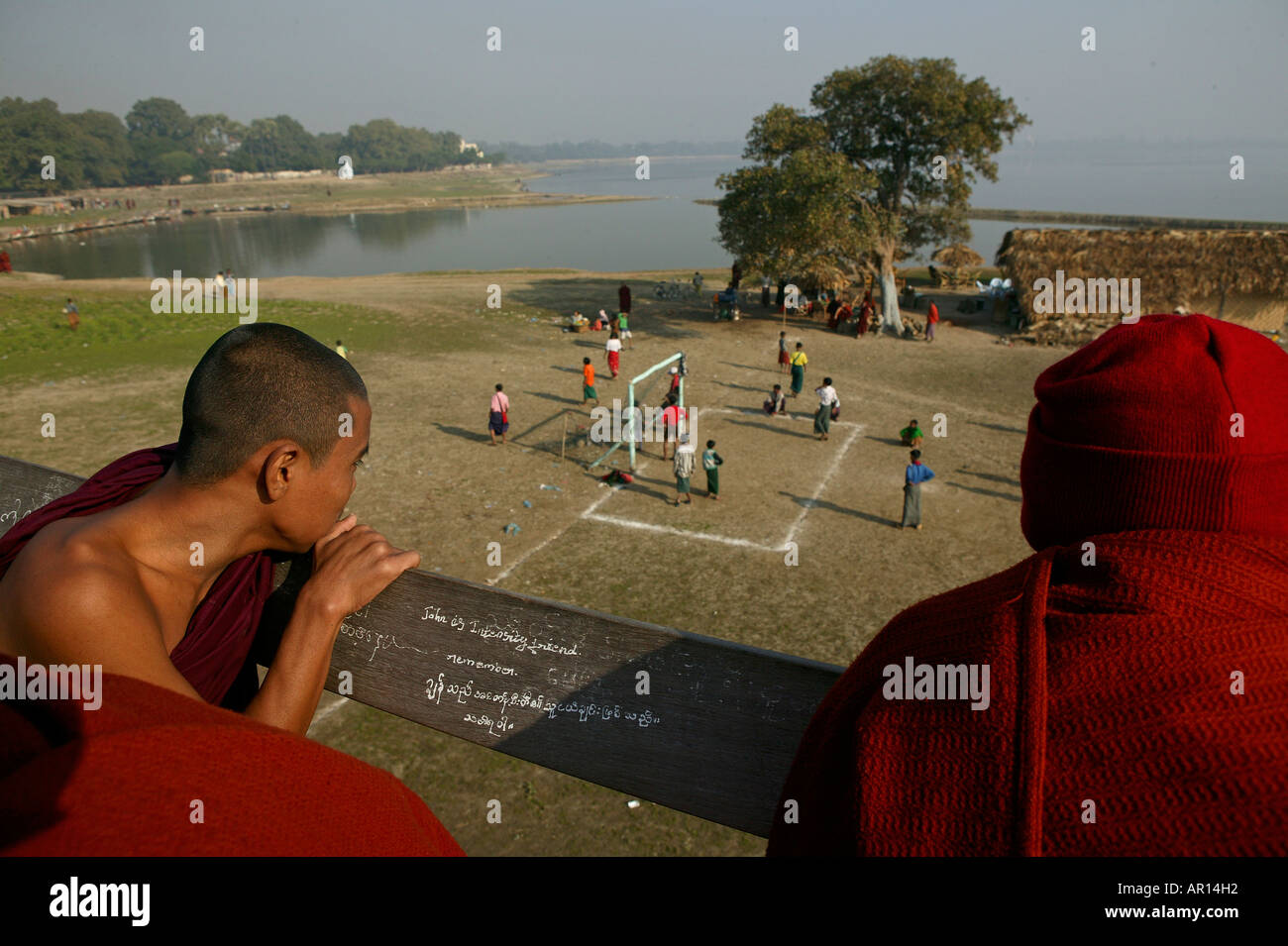 Monks watch football match from U Bein bridge, Moenche beobachten Fussballspiel von der U Bein Bruecke, Amarapura bei Mandalay Stock Photo