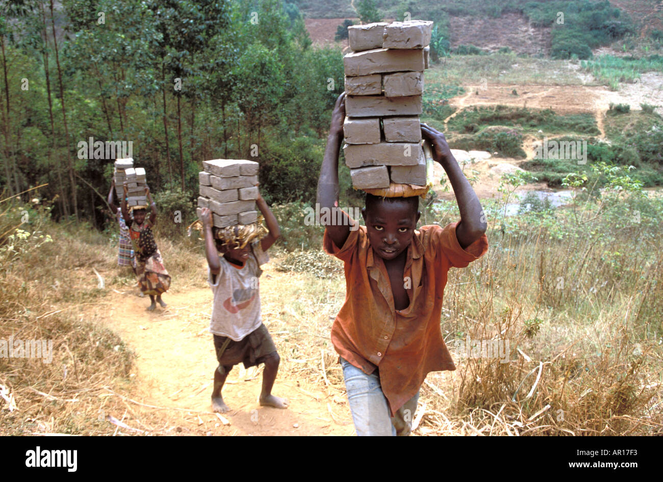Rwandan genocide orphans survive by working carrying bricks up mountainside to repair their destroyed homes Stock Photo