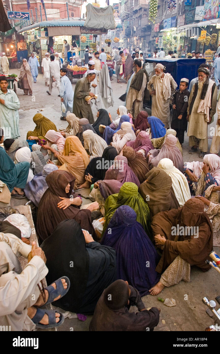 Local women wearing the traditional Bourqa receiving bread inside Peshawar bazaar Peshawar Pakistan Stock Photo