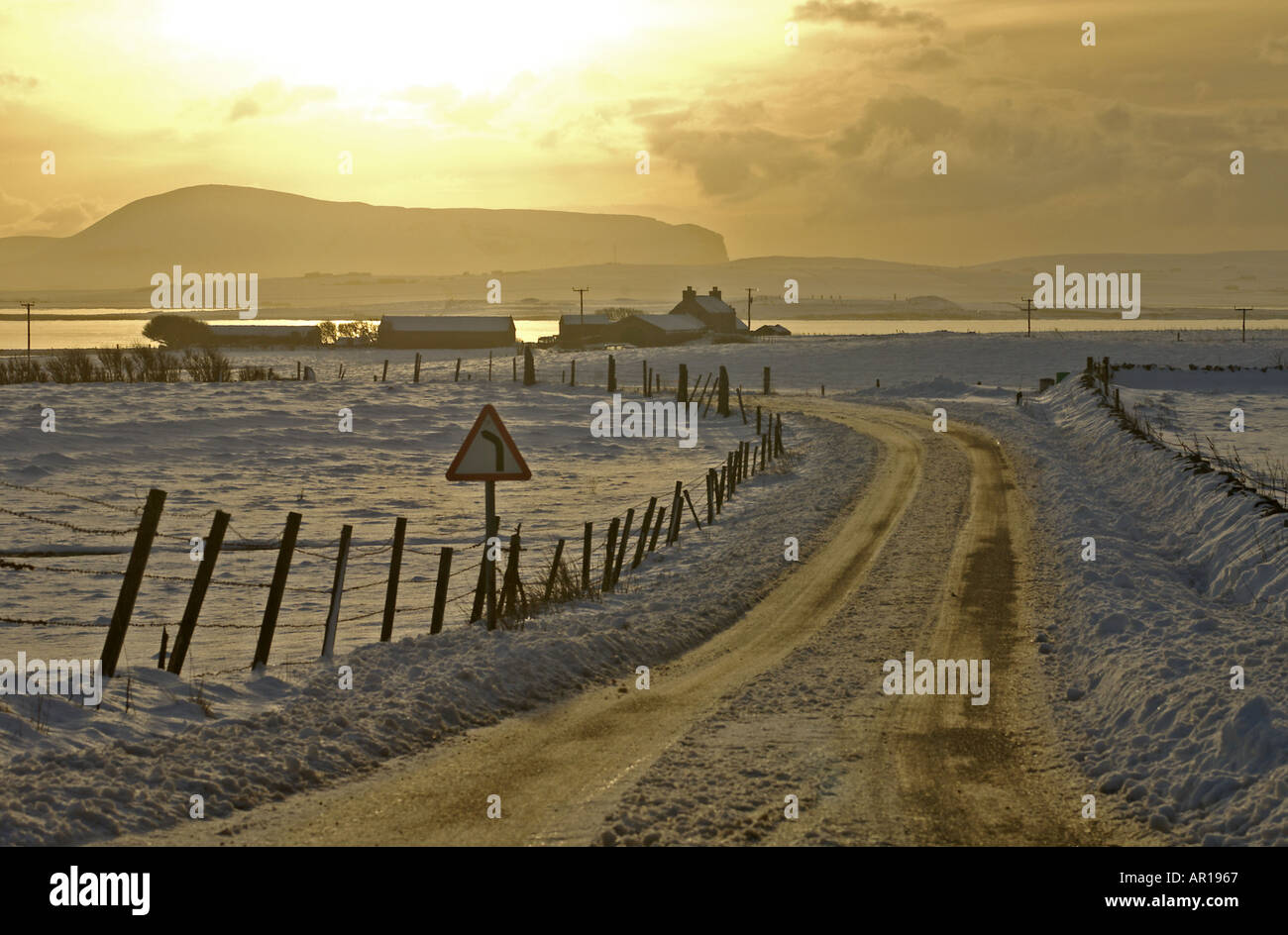 dh Loch of Harray HARRAY ORKNEY Bronze dusk snowy fields and house Loch Harray and Stenness Hoy hills remote winter snow rural road scotland uk Stock Photo