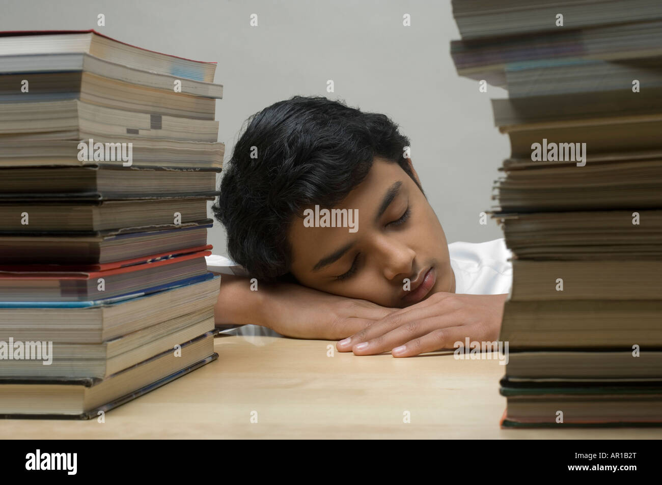 Teenage boy sleeping in front of books stack Stock Photo - Alamy