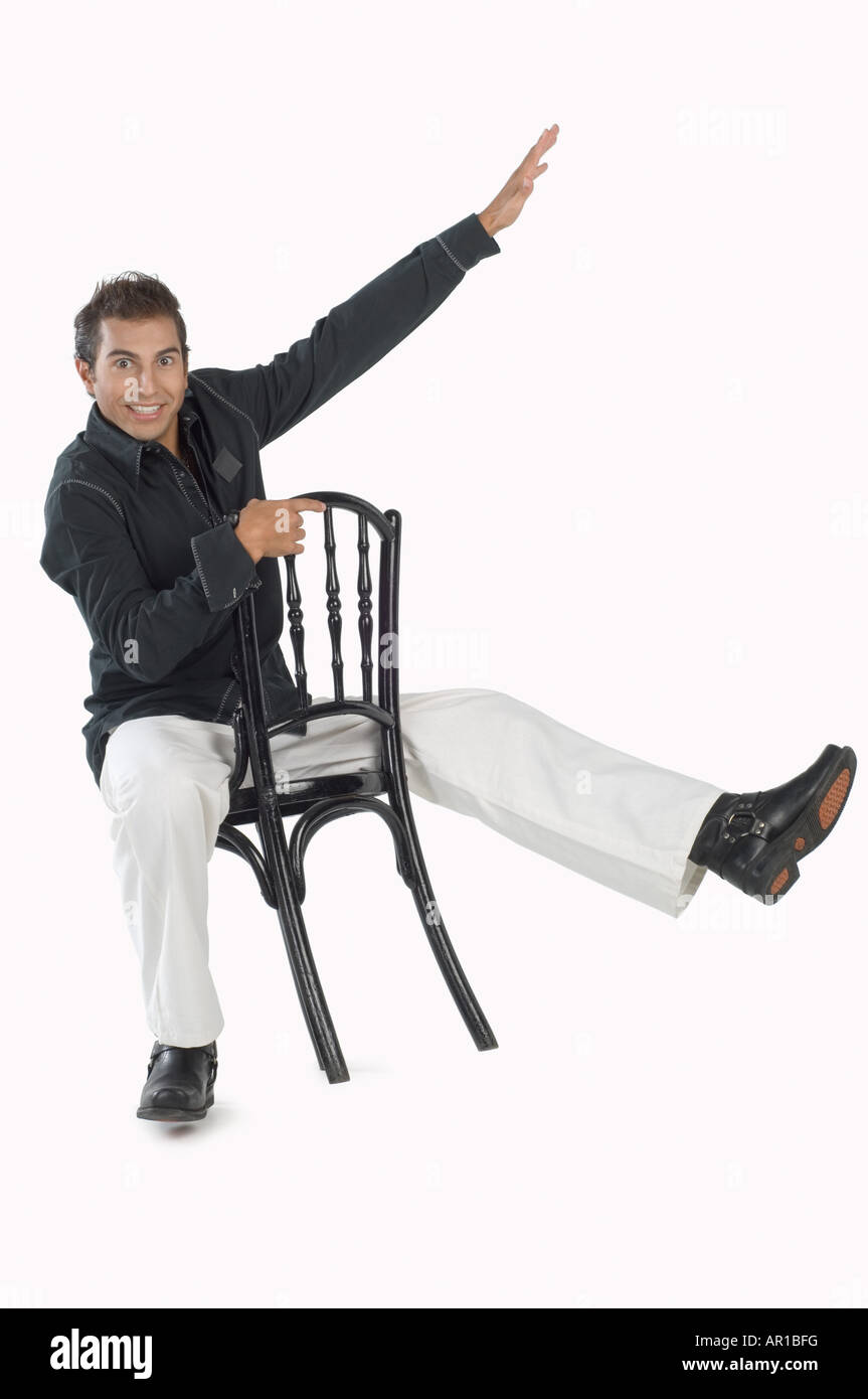 Young man sitting on chair, smiling, portrait Stock Photo Alamy