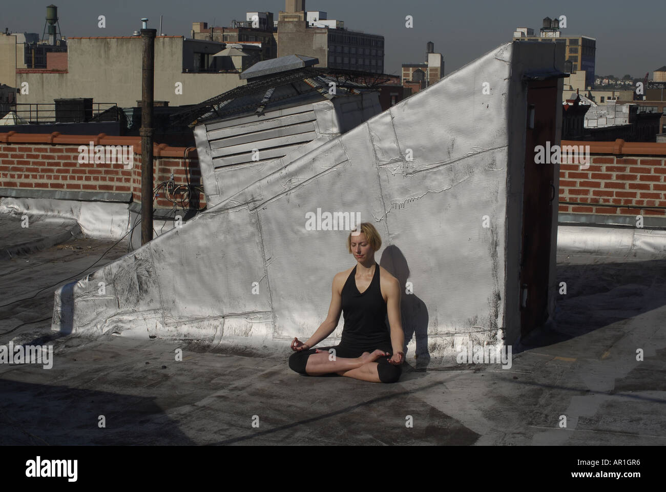Model released New York CIty Thirty years old blond woman dancing on a building roof in a sunny morning in mid town Manhattan ex Stock Photo