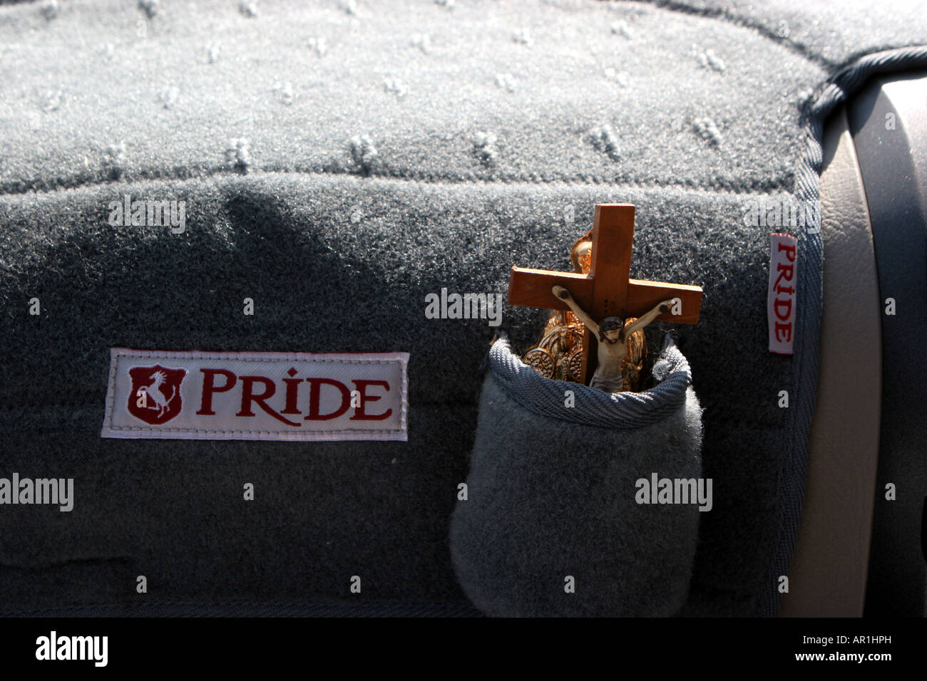 A crucifix sits on the glove compartment of an Indian taxi with car name Pride. Stock Photo