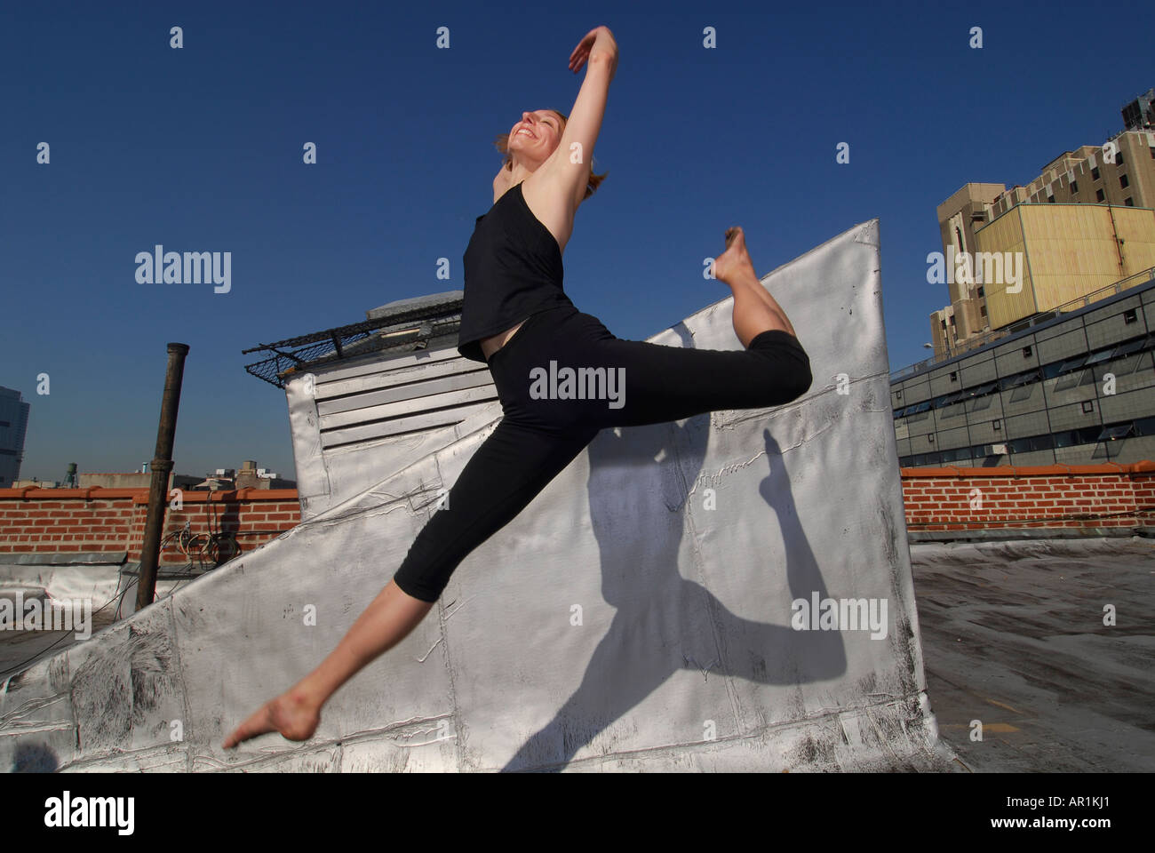 Model released New York CIty Thirty years old blond woman dancing on a building roof in a sunny morning in mid town Manhattan ex Stock Photo