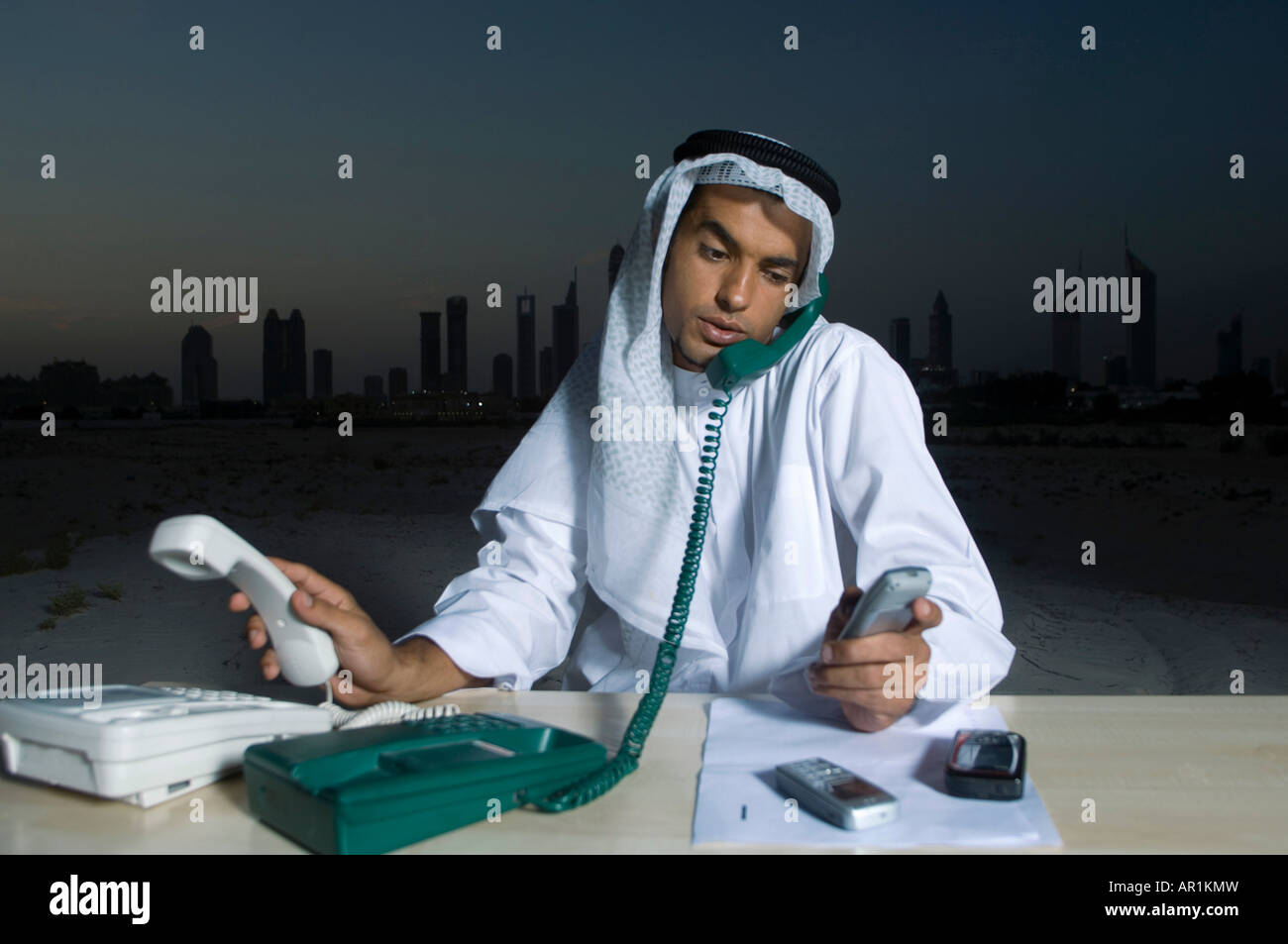 Busy Young Arab Businessman sitting at a desk with Dubai City in the