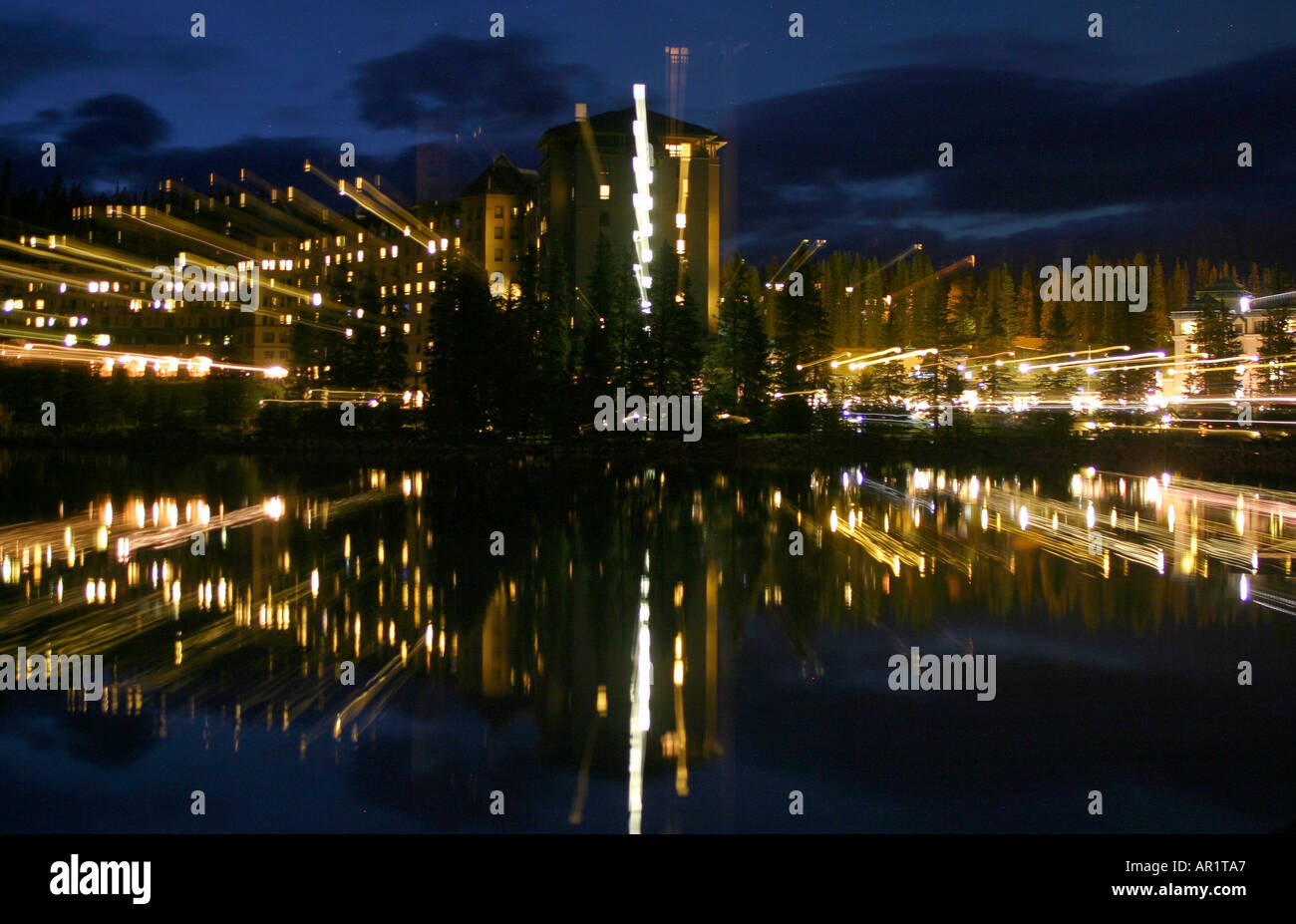 LIGHTS; Night photo of a large hotel and its reflection in a nearby resort lake.  Chateau Lake Louise, Banff National   Park Stock Photo