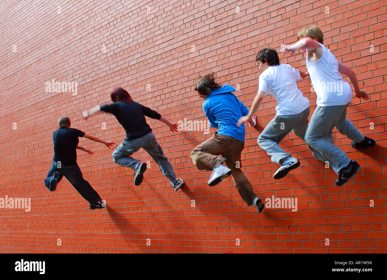 5 parkour boys spring-leap from a brick wall Stock Photo