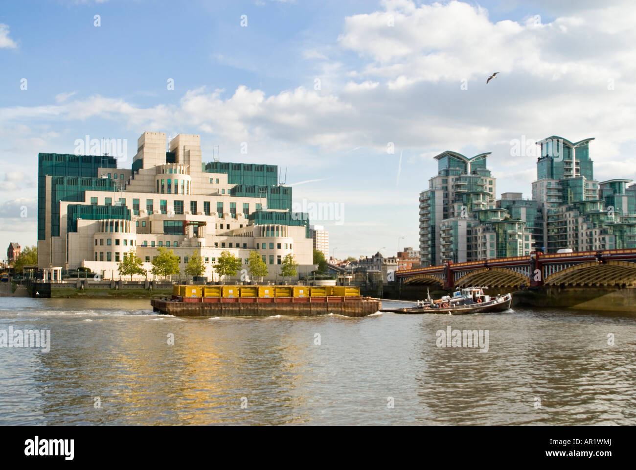 Horizontal view of a tugboat on the River Thames infront of the SIS building aka the MI6 building in Vauxhall on a sunny day Stock Photo