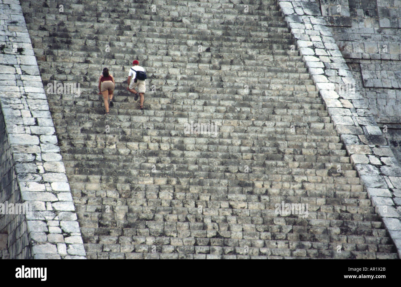 Tourists climbing the steep stairs of El Castillo Pyramid at Chichen