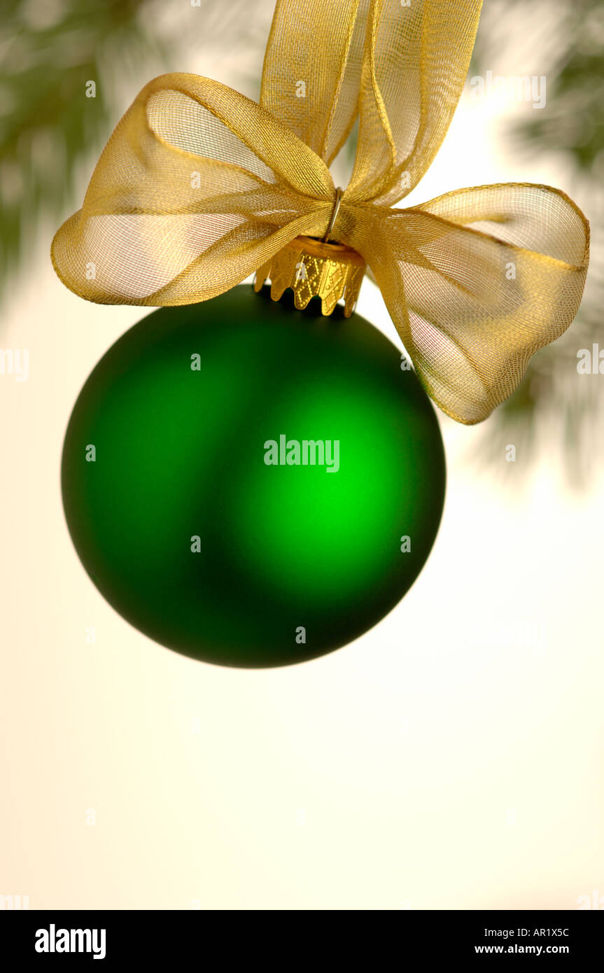 close up of one single green Christmas ball and golden bow hanging on tree Stock Photo