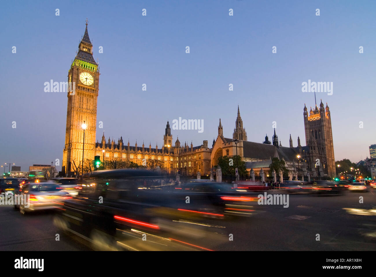 Horizontal wide angle of the Houses of Parliament and Big Ben in Westminster with traffic zooming passed illuminated at night. Stock Photo