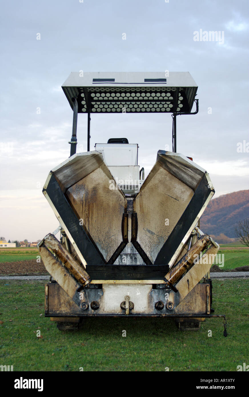 Small asphalt spreader waiting by the old used road in the countryside
