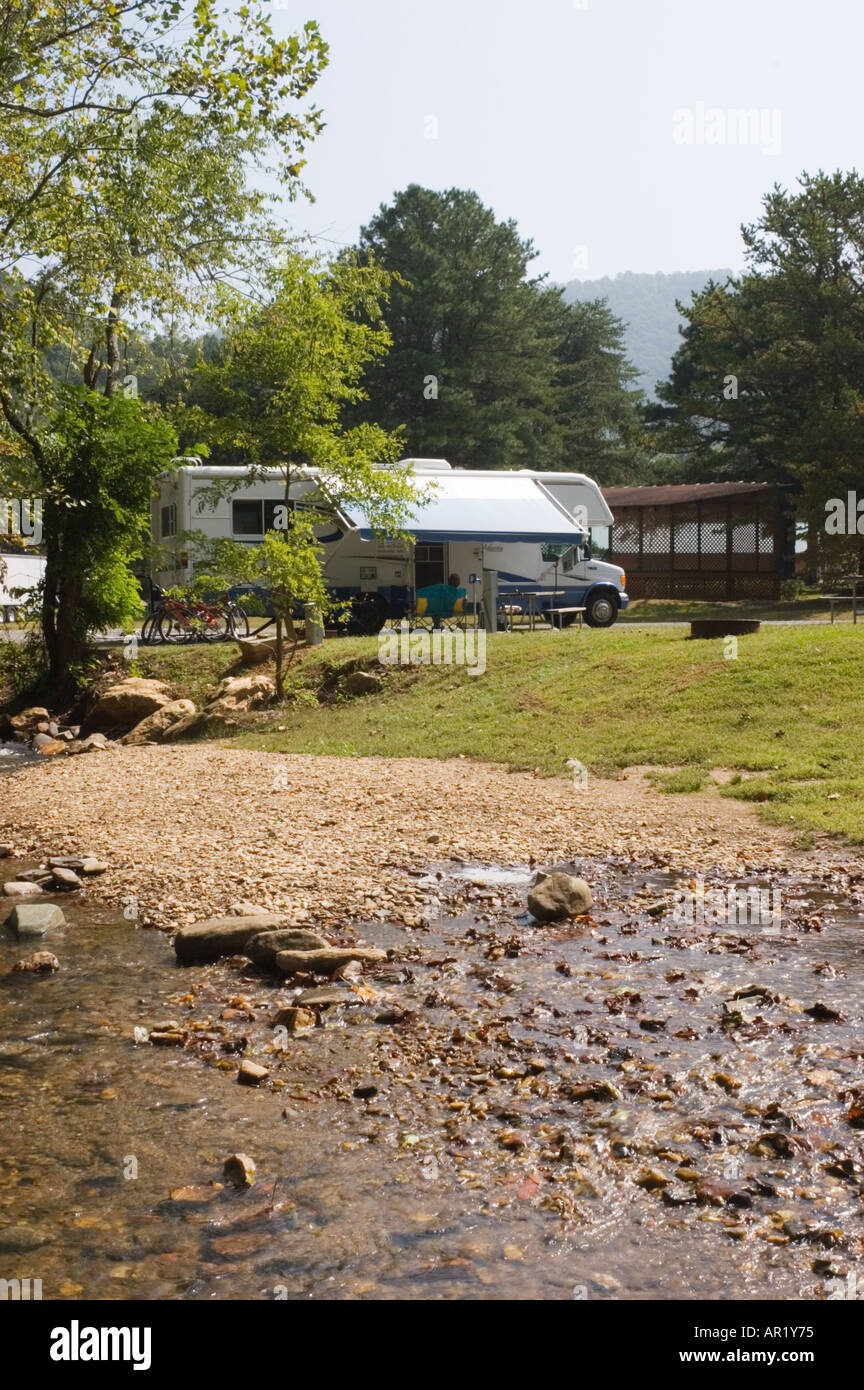 Motorhome camper parked beside creek in private mountain campground in