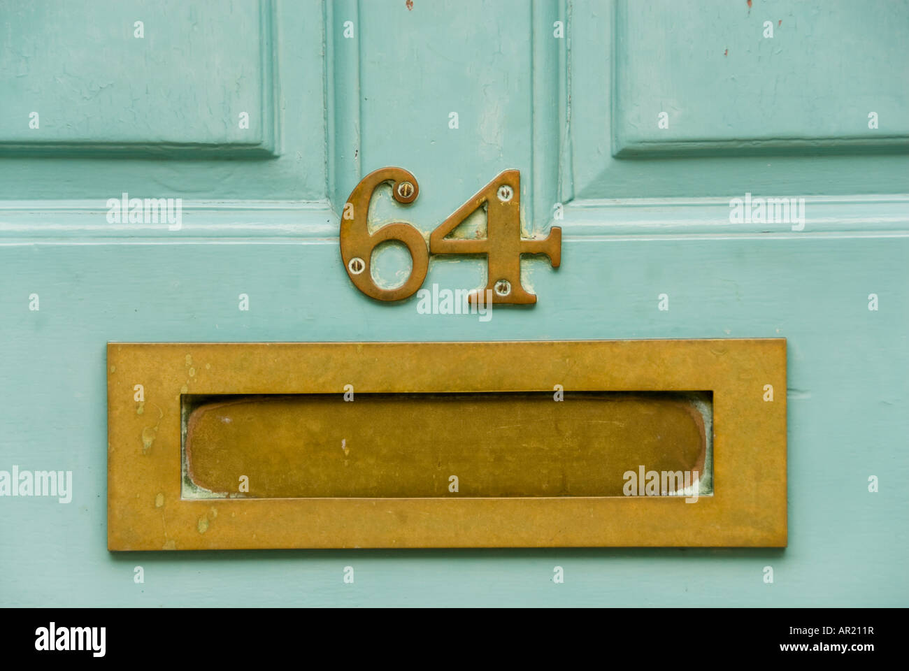 Close-up of brass letterbox in brightly coloured door of number 64 Stock Photo