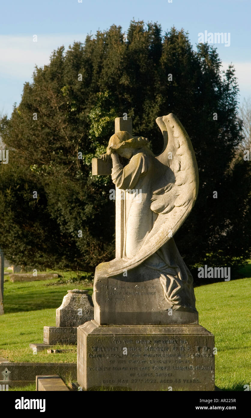 An angel gravestone statue near some trees in the sun and blue sky