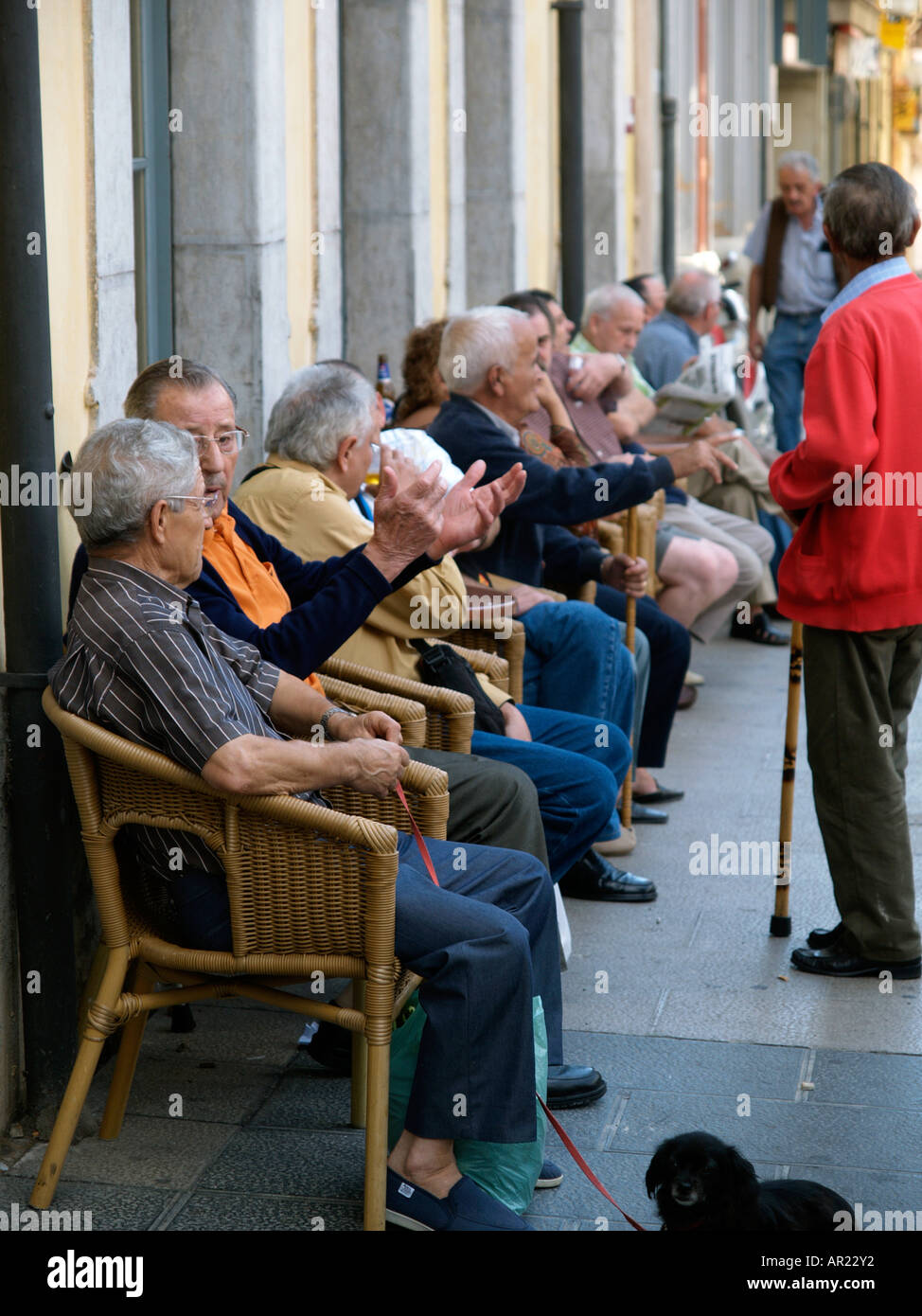 Old men of the town of Palafrugell sit and talk amongst themselves outside a cafe in teh town square Costa Brava Spain Stock Photo