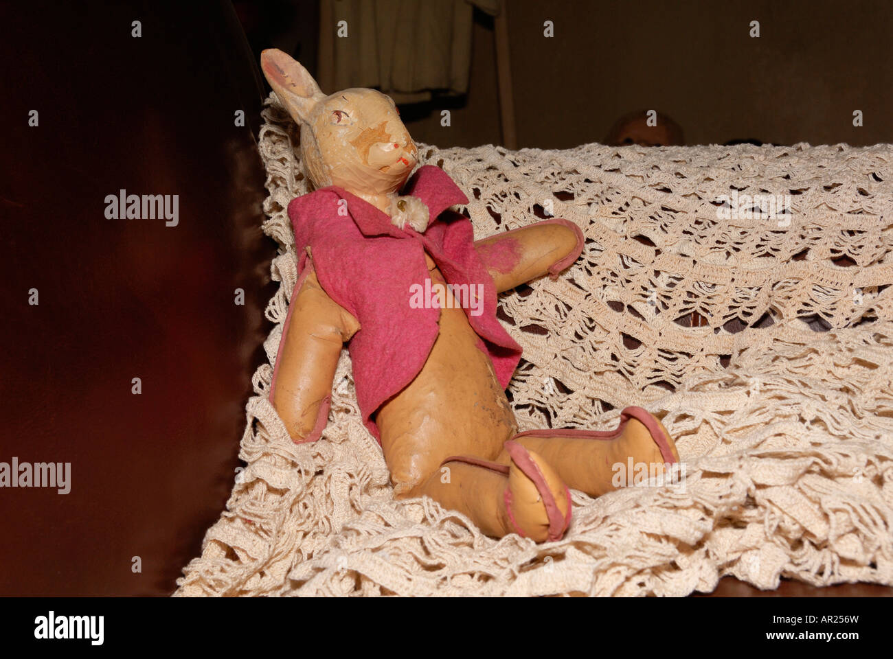 Antique bunny doll on lace afghan sitting on a couch Stock Photo