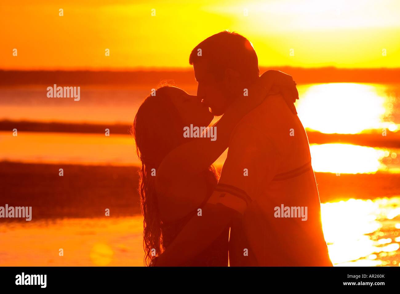 Silhouette of young couple kissing at sunset Stock Photo - Alamy