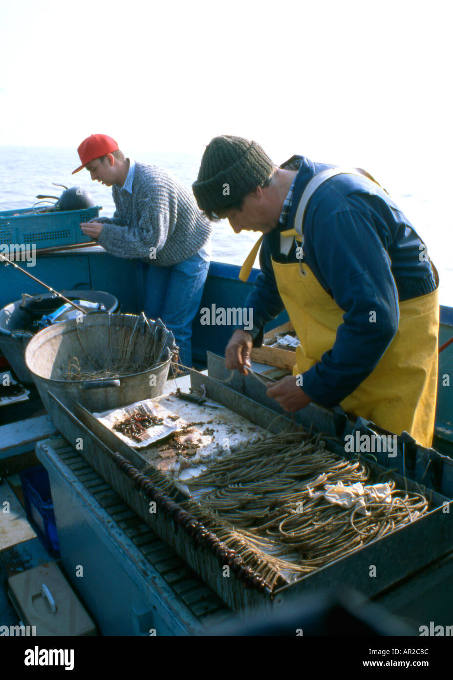 Longshore fisherman baiting lines Stock Photo