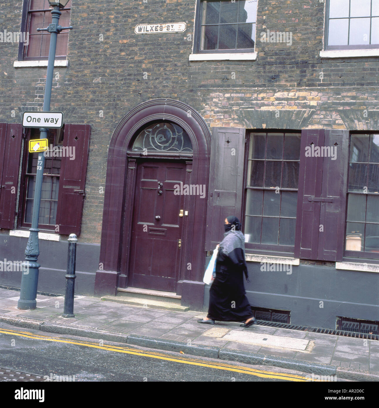 Muslim woman wearing  hijab walking past Huguenot house on Wilkes Street Spitalfields East End London UK  KATHY DEWITT Stock Photo