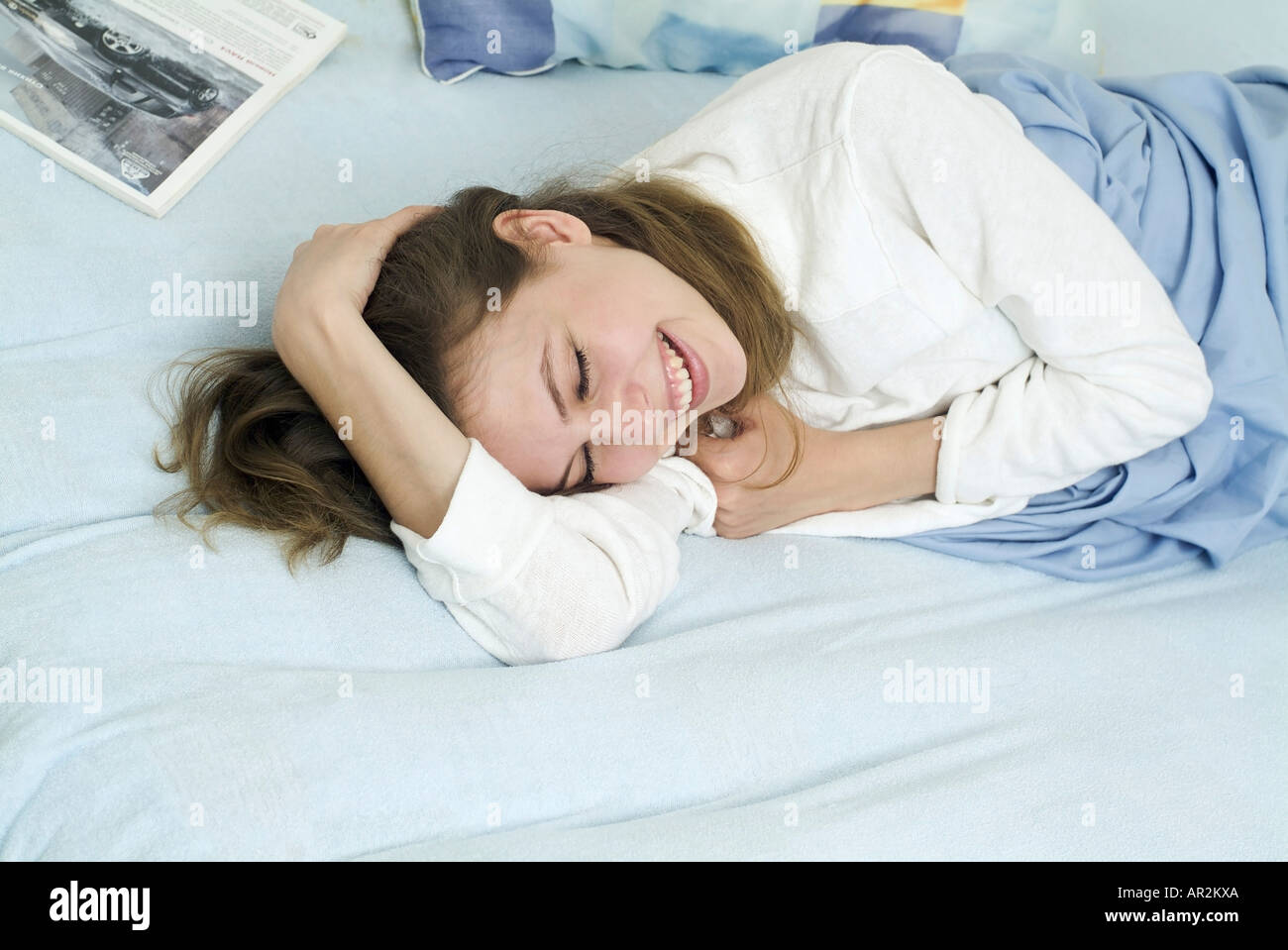 Young woman lying on bed and laughing Stock Photo
