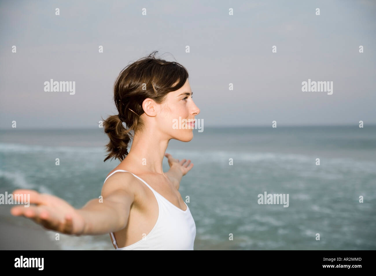 Woman standing on beach with arms outstretched Stock Photo