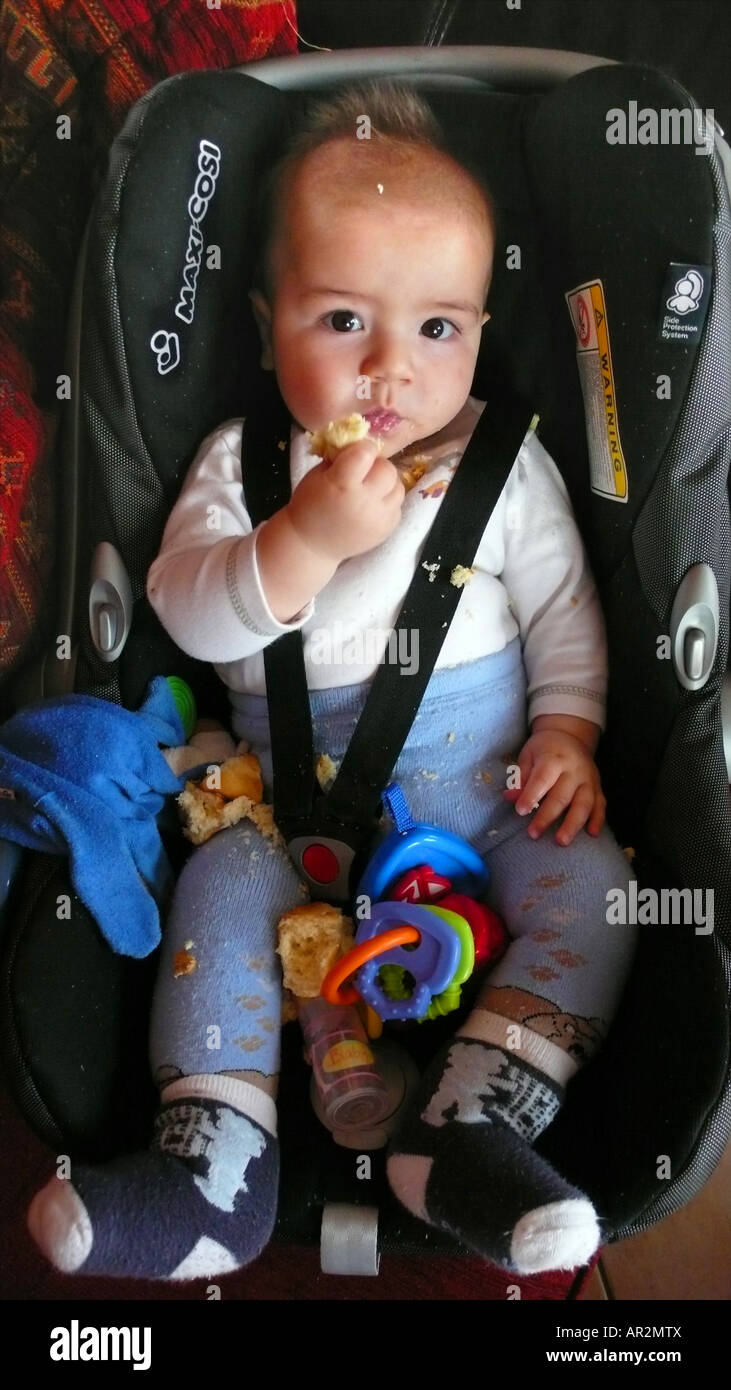 little boy eating bread in child car seat Stock Photo