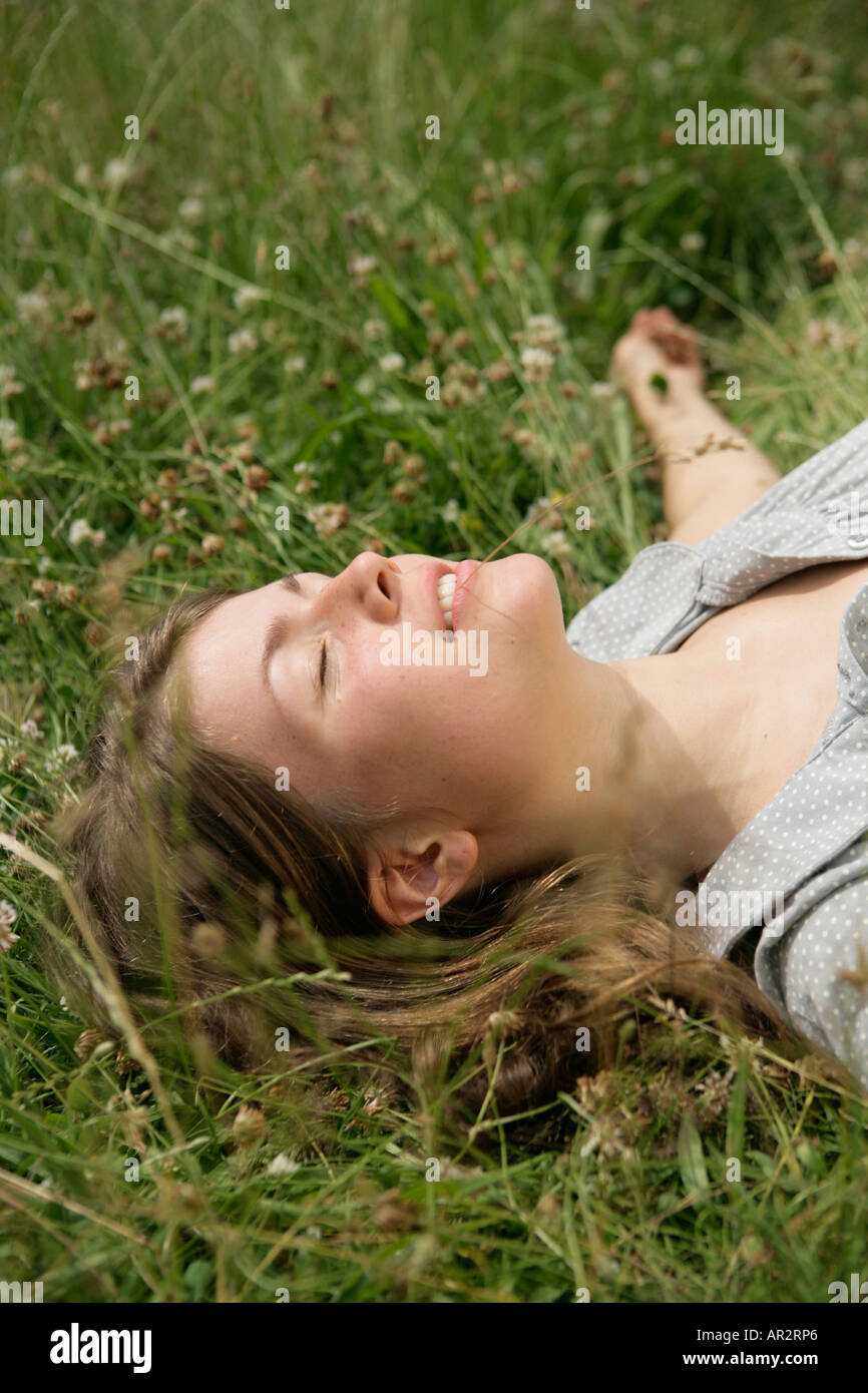 Close up of young woman lying in grass with eyes closed Stock Photo - Alamy