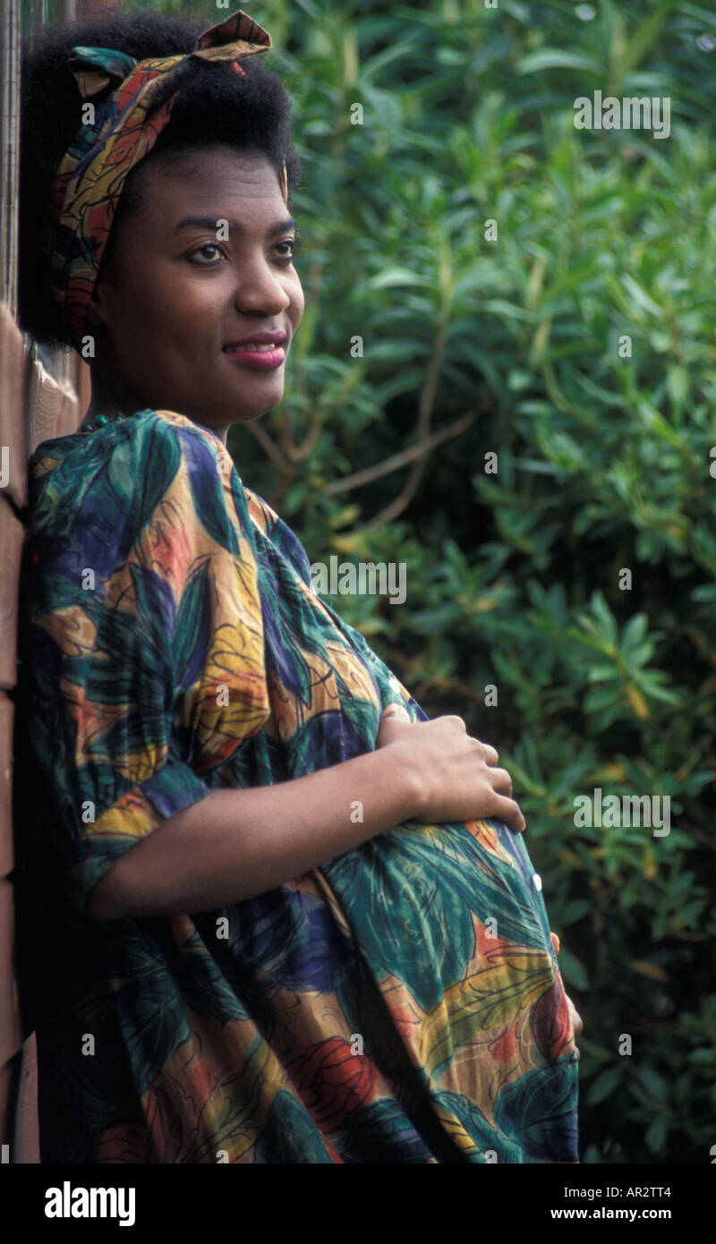 contented heavily pregnant young black woman in green dress outside Stock Photo