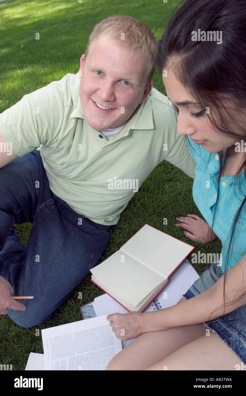 Two people sitting on grass working together Stock Photo